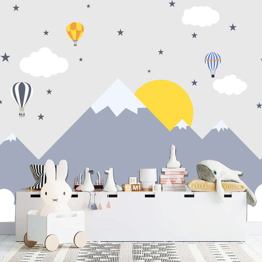 Mountain hot air balloon children's wallpaper | Children's room — Creative mountain and hot air balloon decor in a playful children's room with whimsical clouds, sun, and pastel-toned toys.