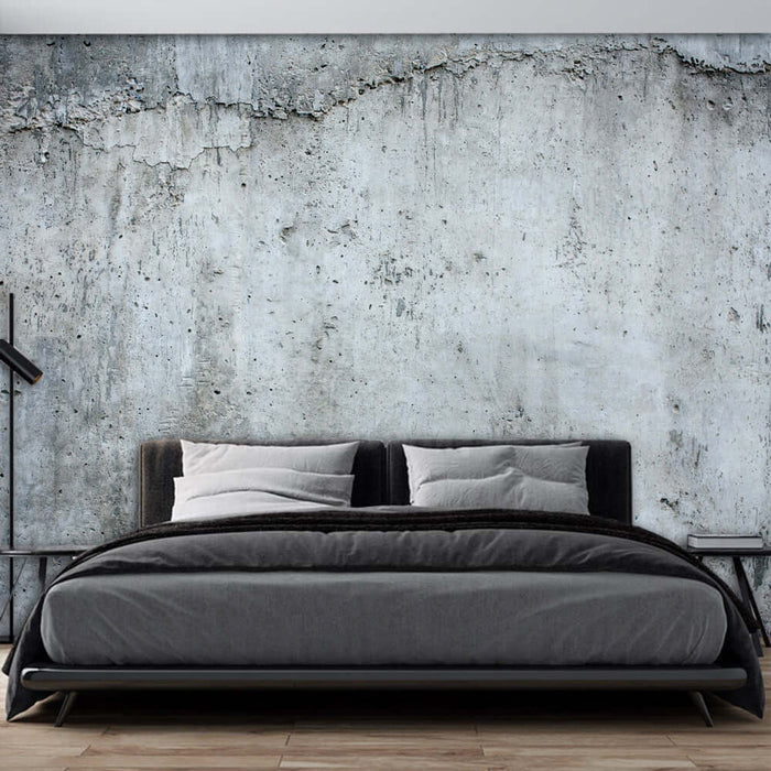 Retro industrial cement wallpaper in a bedroom with a black bed and a textured concrete wall.
