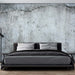 Retro industrial cement wallpaper in a bedroom with a black bed and a textured concrete wall.