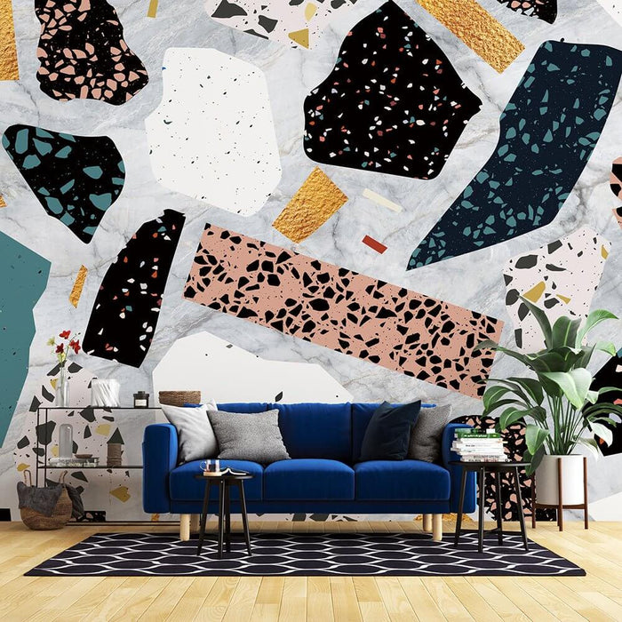 Colorful terrazzo wallpaper mural | trendy collage style wallpaper in a modern living room with bold terrazzo patterns on a feature wall behind a blue sofa