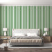 Green and white vertical striped wallpaper | Living room and bedroom decorative wall — bold green white stripes behind a modern white upholstered bed with neutral bedding and minimalist bedside tables