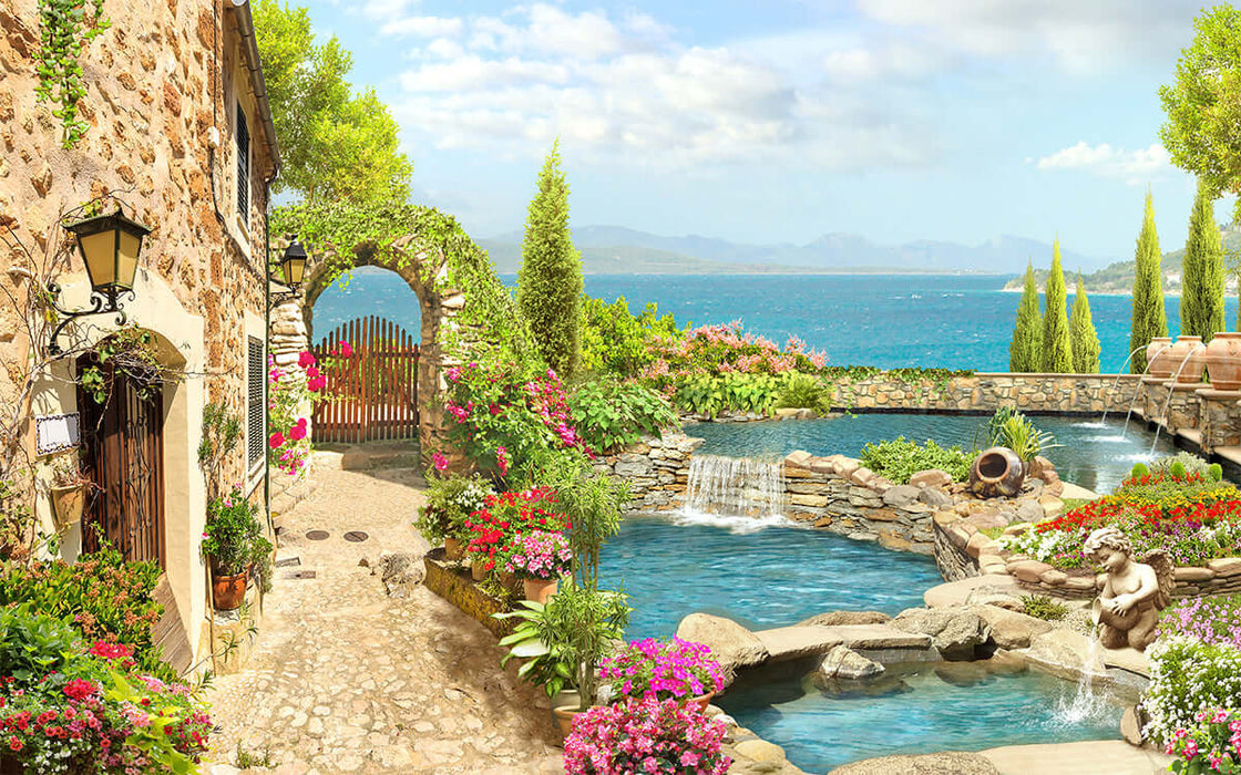 Mediterranean courtyard wallpaper | Sea view garden style mural with stone pathway, archway, lush flowers, terraced pool, and  coastal blue sea view