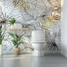 Tropical leaf wallpaper mural | Living room bedroom decorative wall in a luxe bathroom scene showing foliage wallpaper with gold accents and modern toilet