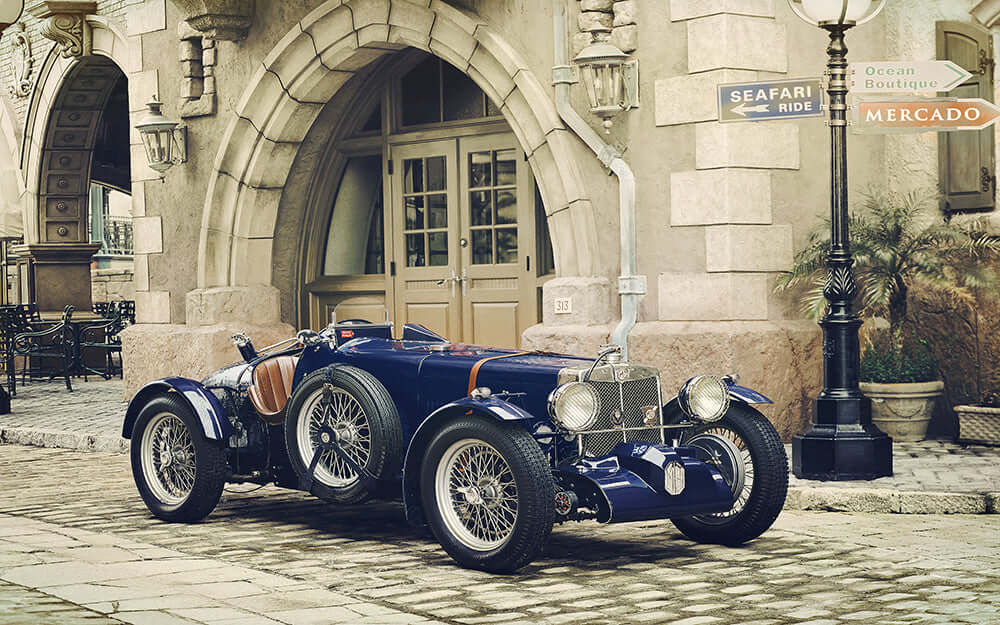 vintage sports car wallpaper featuring a classic car parked by a European street with charming architecture.