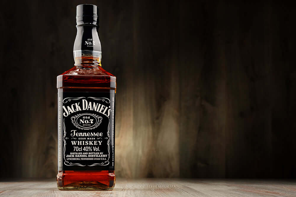 Jack Daniel's whiskey wallpaper featuring a classic No.7 bottle with amber liquor and vintage labels.