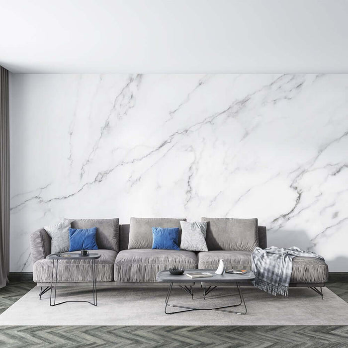 White Marble Textured Wallpaper Mural - Natural Stone Effect in a modern living room with grey sectional, blue cushions, and minimalist coffee tables